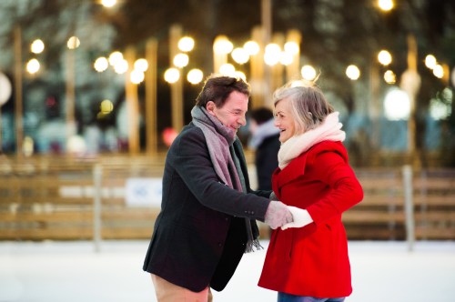 Beautiful senior couple ice skating in city centre. Winter